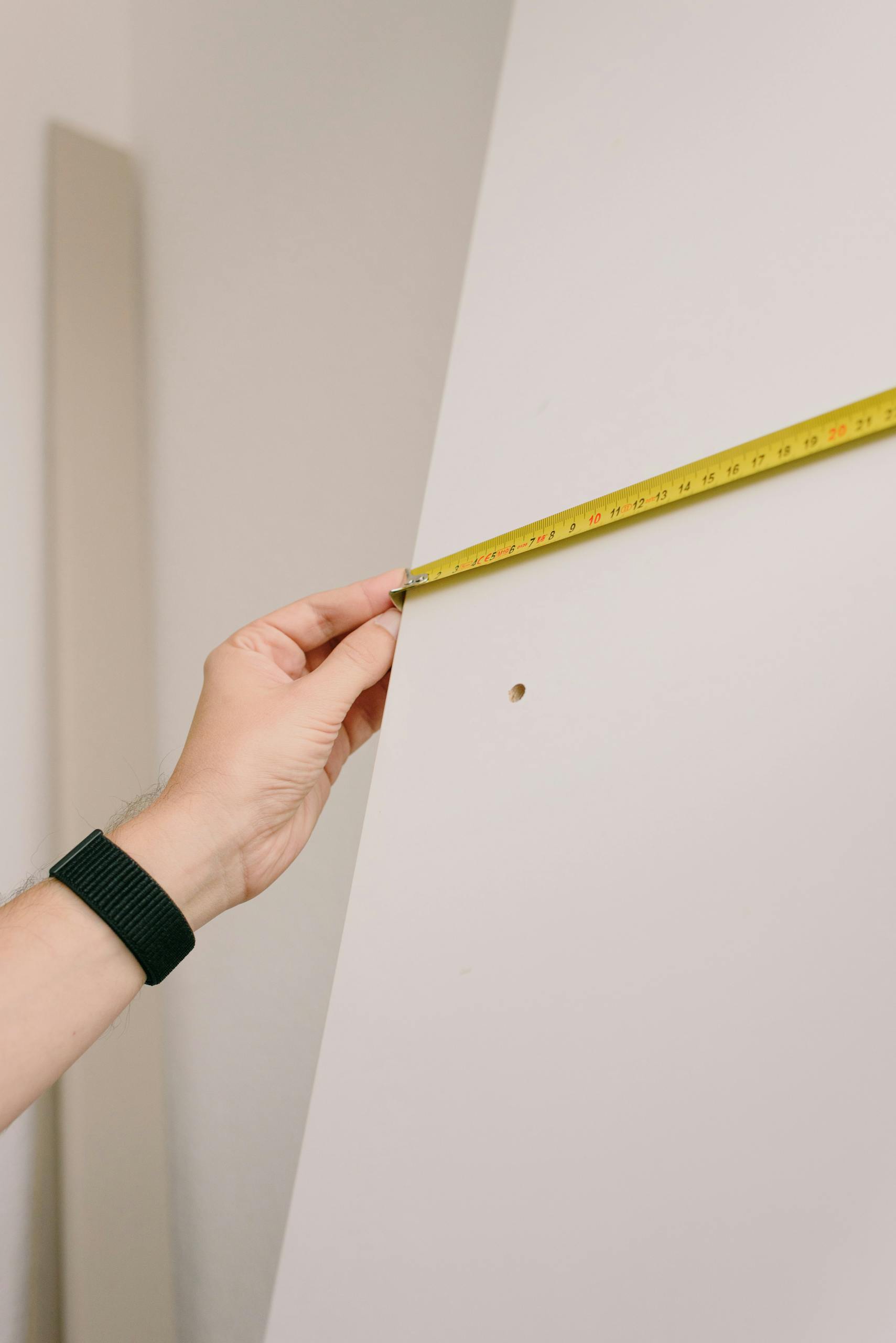 Crop man measuring wall in room